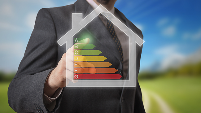 verweist auf: Energieeffizienz von Gebäuden Mann im Anzug steht hinter Hologramm eines Gebäudes, in dem Effizienzklassen dargestellt sind (verweist auf: Energieeffizienz von Gebäuden)