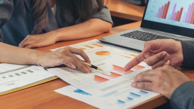 Das Bild zeigt einen Ausschnitt von zwei Geschäftsleuten, die sich im Konferenzraum beraten. Auf dem Tisch liegen diverse Diagramme und ein aufgeklappter Laptop. Das Bild zeigt einen Ausschnitt von zwei Geschäftsleuten, die sich im Konferenzraum beraten. Auf dem Tisch liegen diverse Diagramme und ein aufgeklappter Laptop.